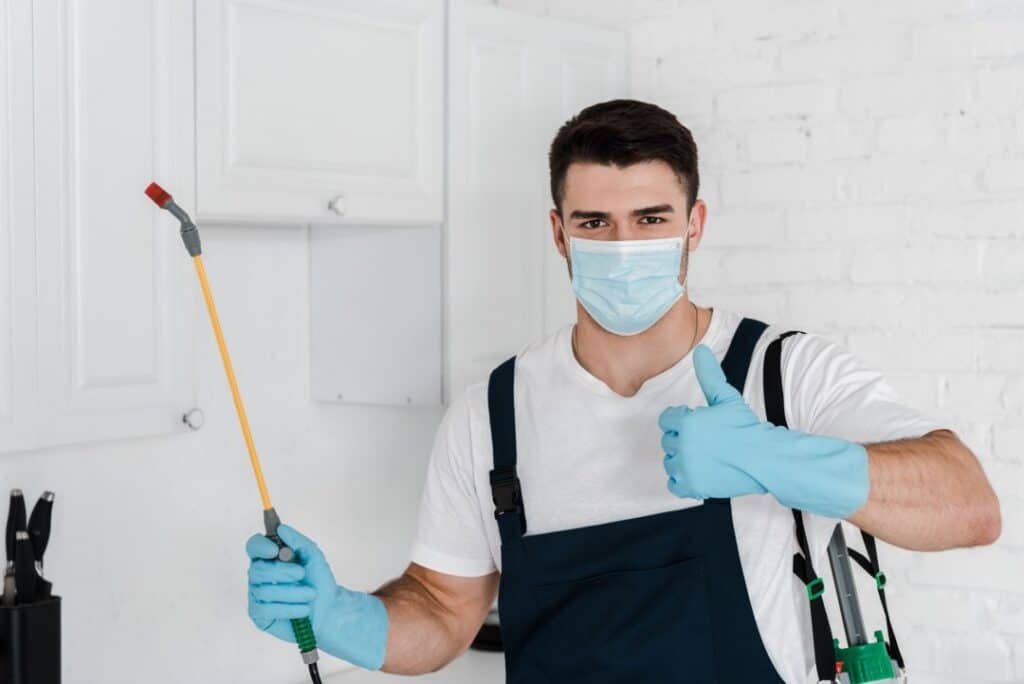 exterminator in uniform holding toxic spray and showing thumb up 1 Accueil